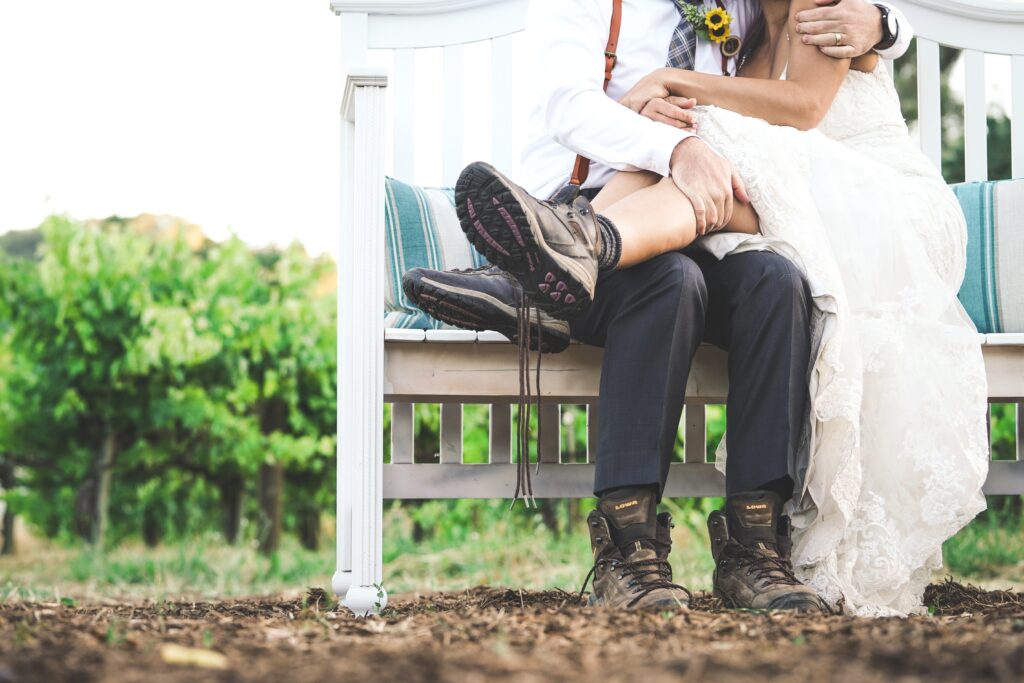 newly married couple sitting on bench wearing hiking boots