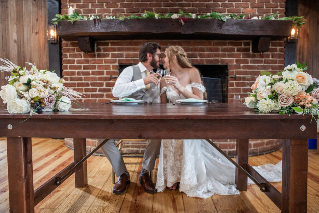 bride and groom kissing at table in front of fireplace