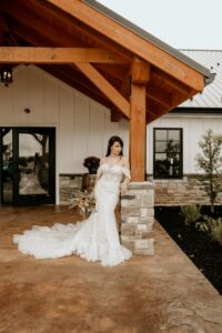 bride posing against pillar by front entrance