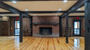 rustic room with dark wood beams and brick fireplace